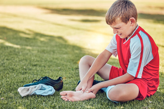 child playing football removing boot and sock as heel in pain